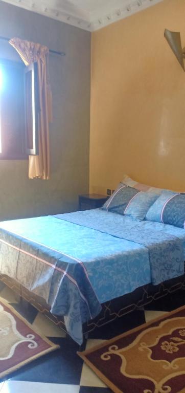 1 dormitorio con cama con sábanas azules y ventana en Dar LBAHJA 2, en Ouzoud