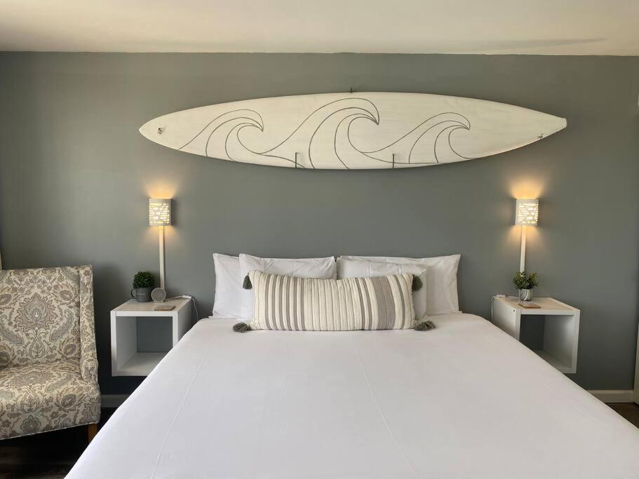a bedroom with a large white bed with a surfboard on the wall at Nalu Malu 1 Bedroom @Waikiki Banyan 1 Free Parking in Honolulu