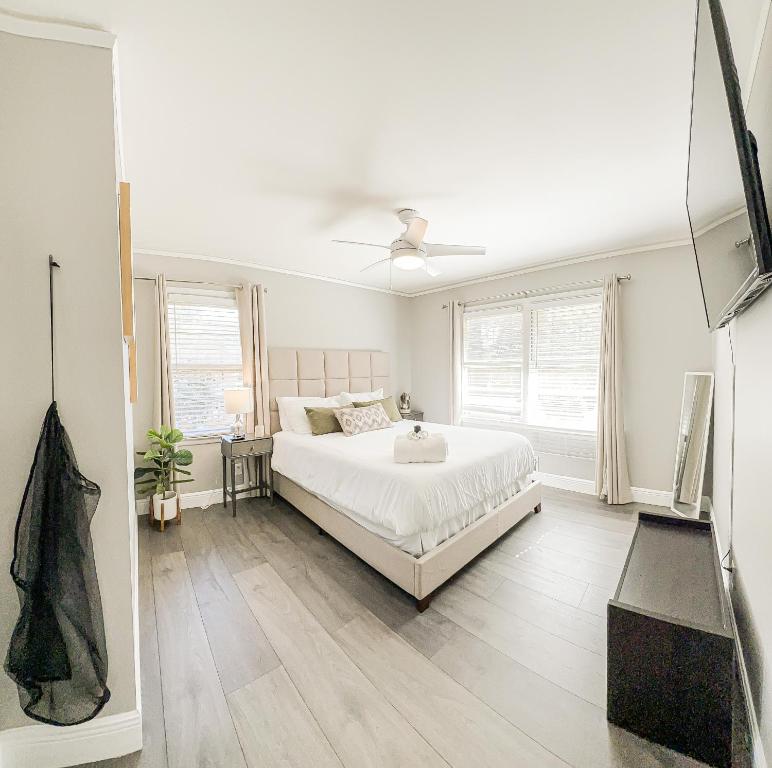 a white bedroom with a large white bed and windows at Retreat with Sauna Near ATL Large Backyard with Deck in Tucker