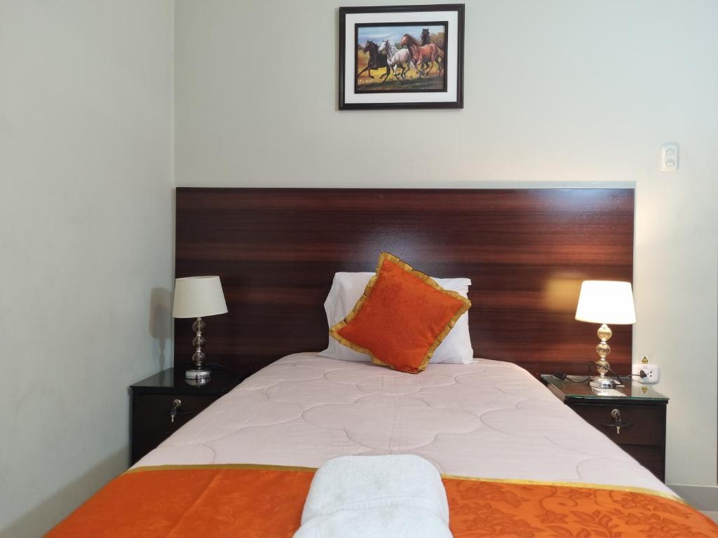 a bedroom with a large bed with a wooden headboard at Hotel Los Nogales in Cajamarca