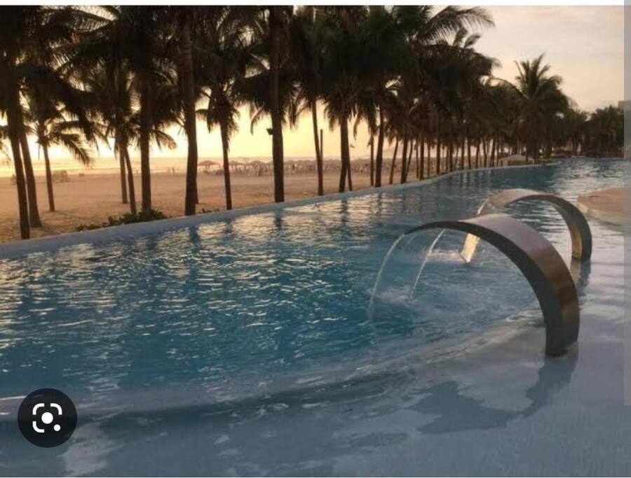 uma piscina com uma fonte de água em frente a uma praia em Hermoso departamento Acapulco em Acapulco