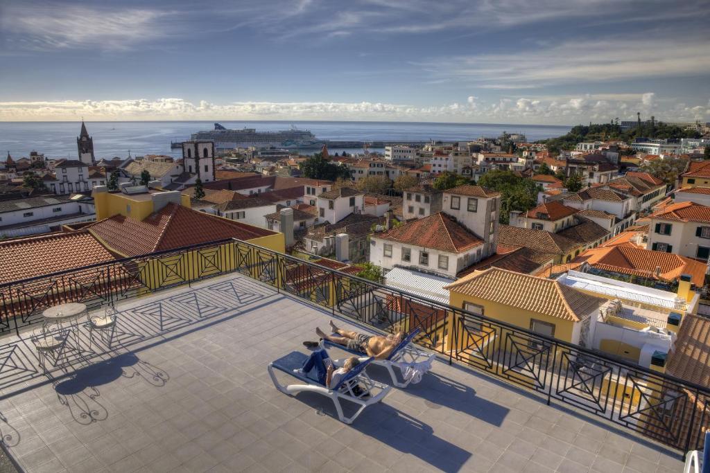 um casal sentado num sofá com vista sobre uma cidade em Hotel Orquidea em Funchal