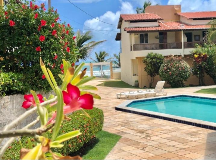 una casa con piscina y una flor en el patio en Duplex Beira-mar em condomínio / Búzios-RN, en Nísia Floresta