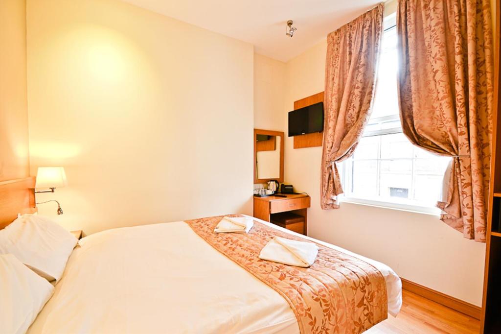 a bedroom with a bed and a window at Kings Cross Inn Hotel in London