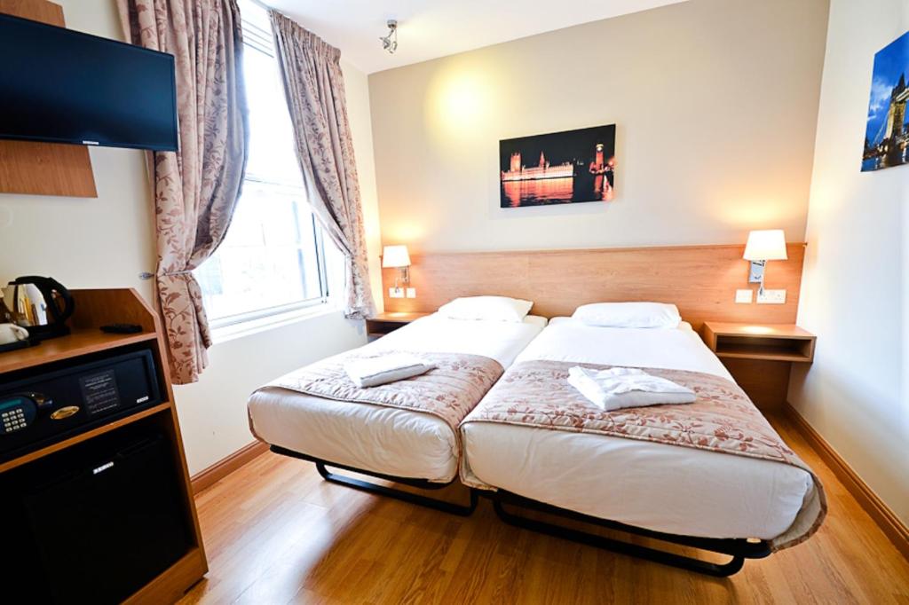 a hotel room with a bed and a flat screen tv at Kings Cross Inn Hotel in London