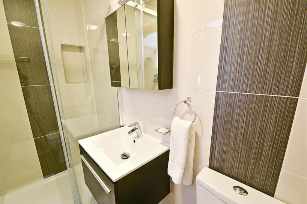 a white bathroom with a sink and a mirror at Kings Cross Inn Hotel in London