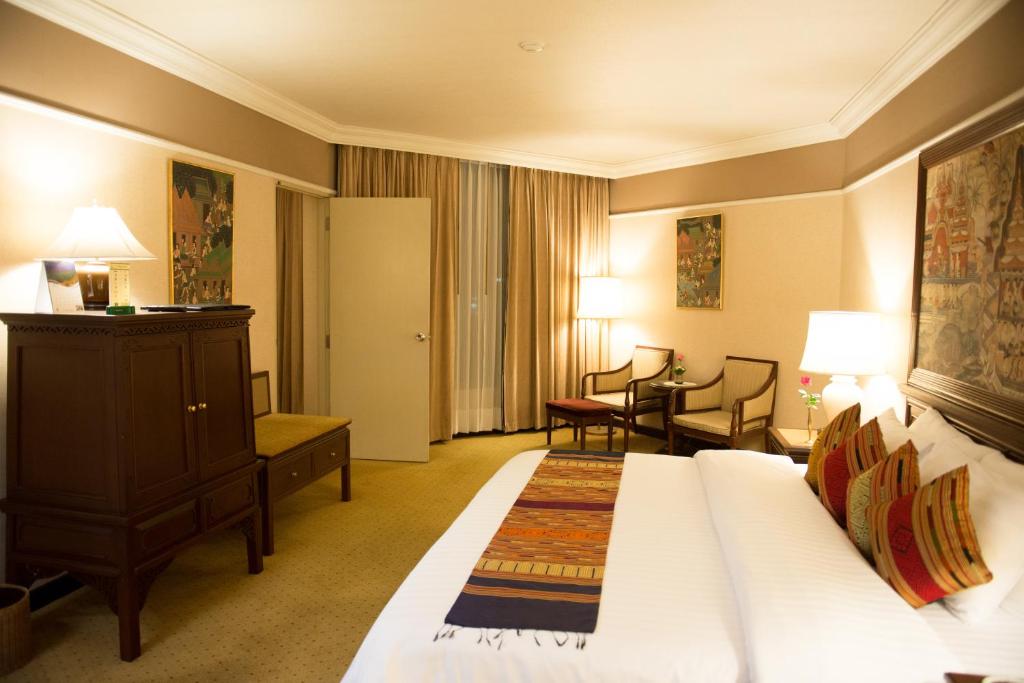 um quarto de hotel com uma cama, uma mesa e cadeiras em Wiang Inn Hotel em Chiang Rai