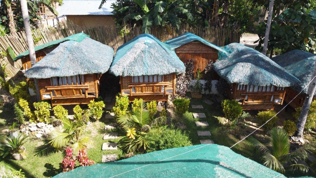 a group of houses with thatched roofs in a garden at Coco Garden Villas in El Nido