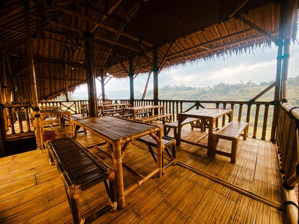 a restaurant with tables and chairs on a deck at Saung Arjuna Syandana Resort in Ciwidey