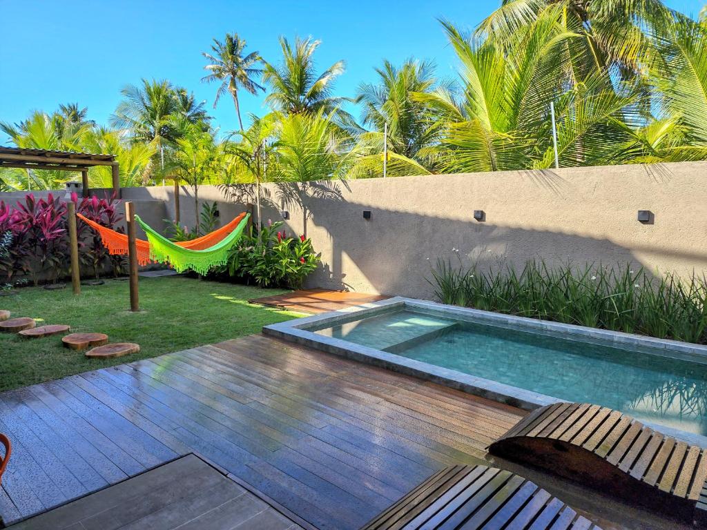 einen Hinterhof mit einem Pool und einer Hängematte in der Unterkunft Kai Milagres Beach House in São Miguel dos Milagres