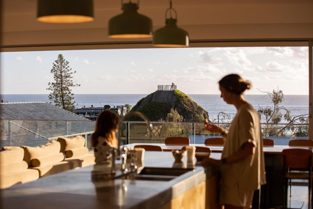 a woman standing in a restaurant with a view of the ocean at Daybreak at Currumbin in Gold Coast