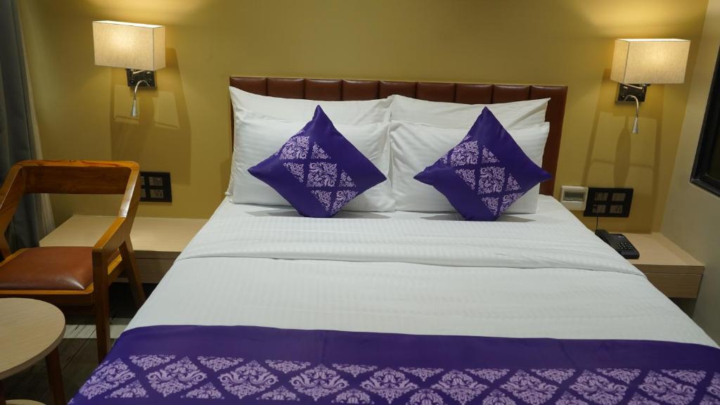 a bed with purple and white pillows in a room at Purple Beds by VITS - Dwarkesh, Surat in Salabatpura