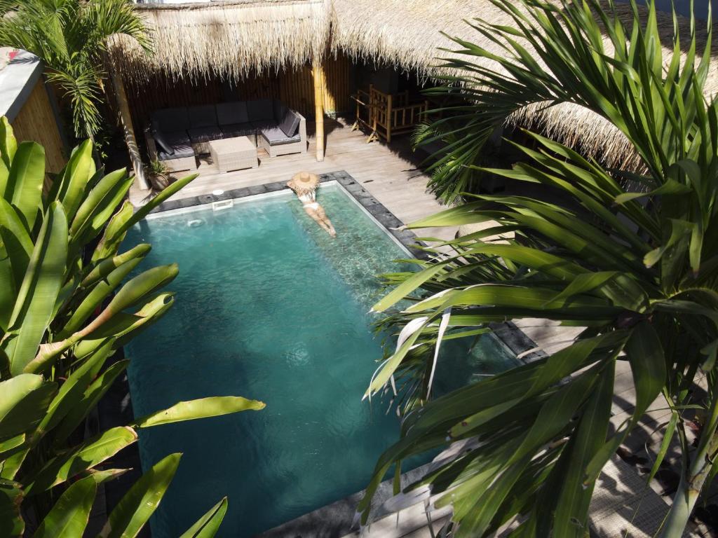 a person swimming in a swimming pool next to a house at Akasia Villas in Gili Islands