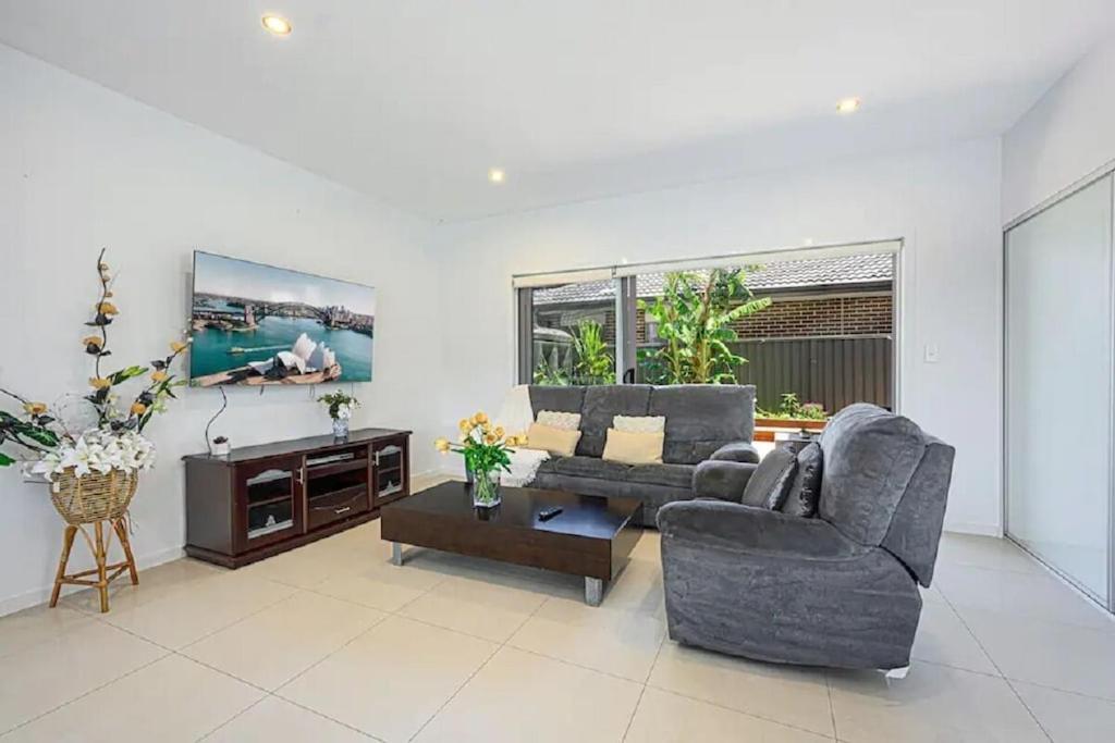 uma sala de estar com dois sofás e uma mesa em Spacious 5 Bedroom 2.5 bathroom House in Gregory Hills em Narellan