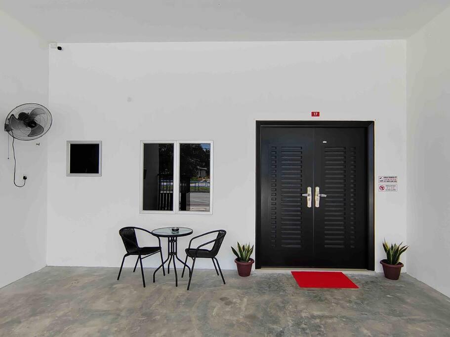 a room with a table and chairs and a black door at New Single Storey Homestay @ Sitiawan 3R2B (6-9PAX) _Feb Moment Homestay in Sitiawan