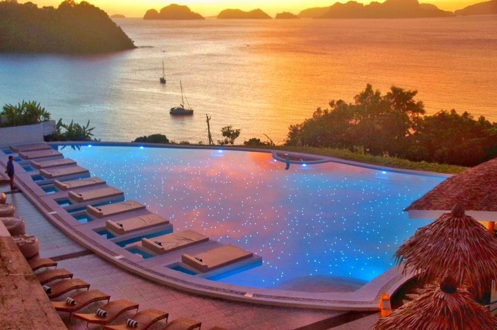 a swimming pool with chairs and a view of the water at El Nido Bayview Resort in El Nido