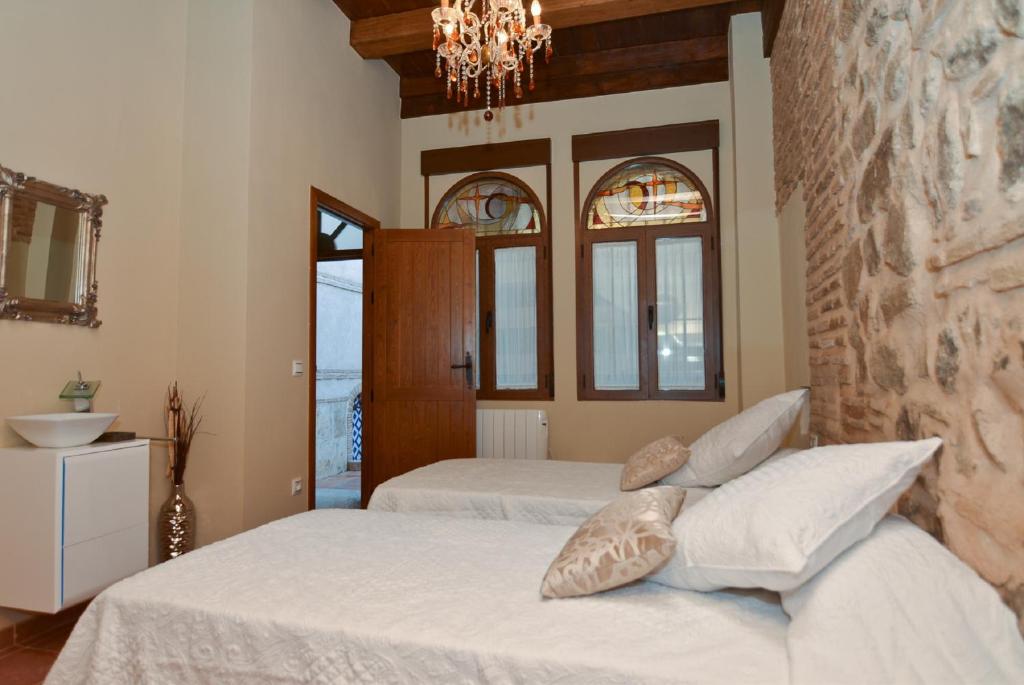 a bedroom with two beds and a stone wall at Apartamentos La Casa Del Grial in Toledo