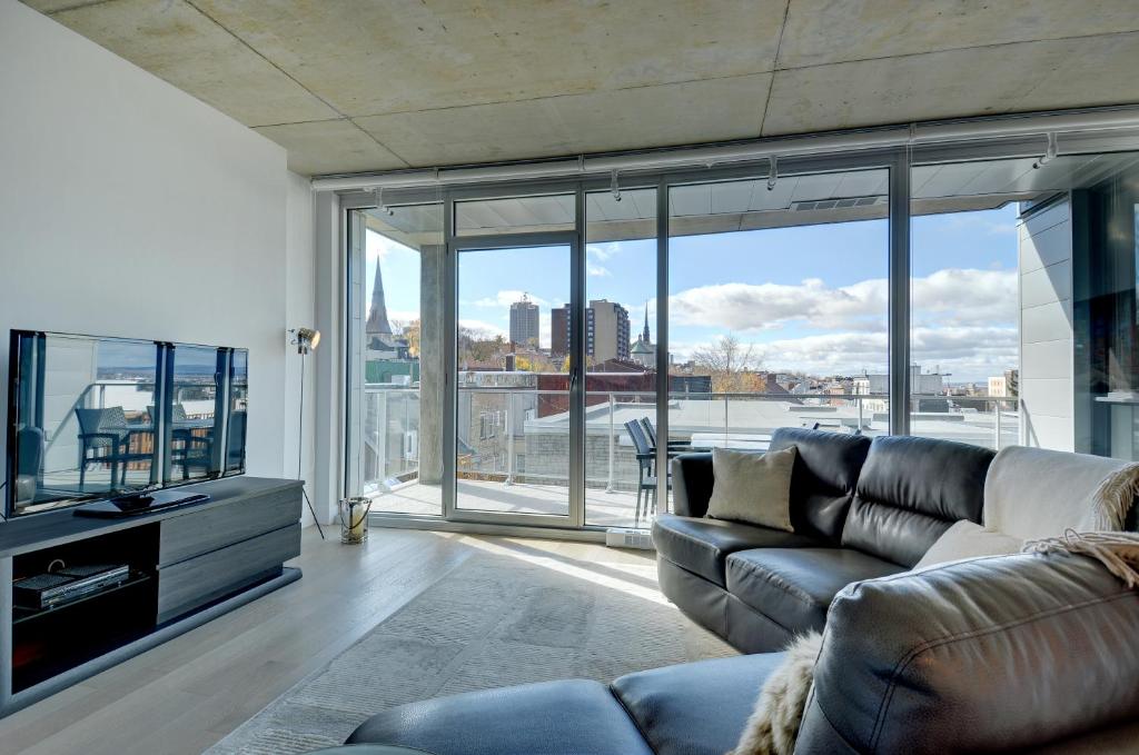 un soggiorno con divano e una grande finestra di Les Immeubles Charlevoix - Le 760516 a Québec
