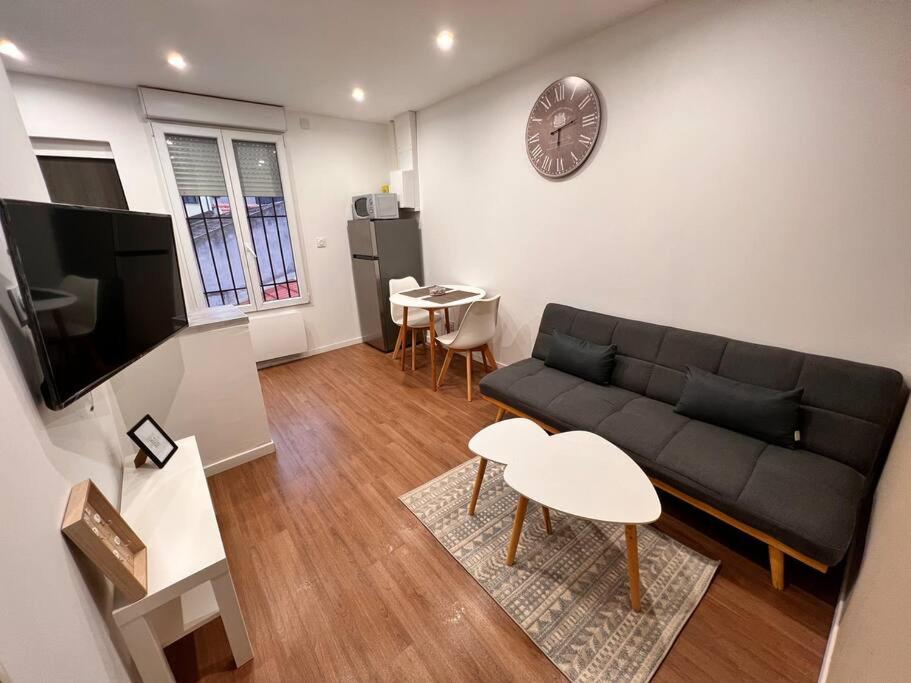 salon z kanapą i zegarem na ścianie w obiekcie Arcueil 2P Moderne Proche RER B w mieście Arcueil