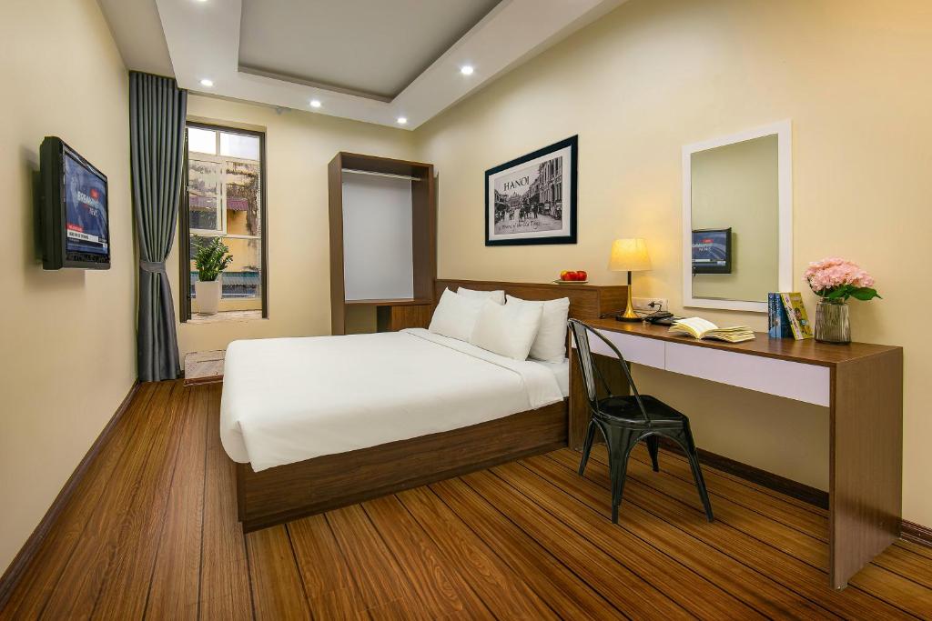 a hotel room with a bed and a desk at Queen Cafe Hotel & Pub in Hanoi