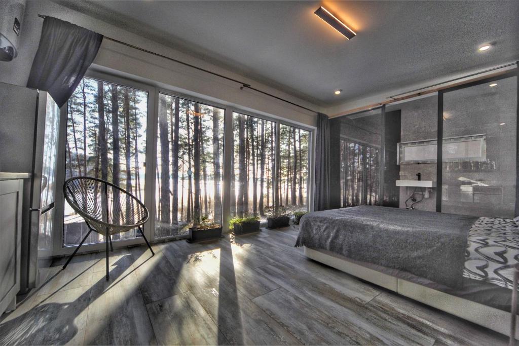 a bedroom with a bed and large windows with trees at BOSE and Bang&Olufsen lofts on a lake by Gauja Club in Gauja