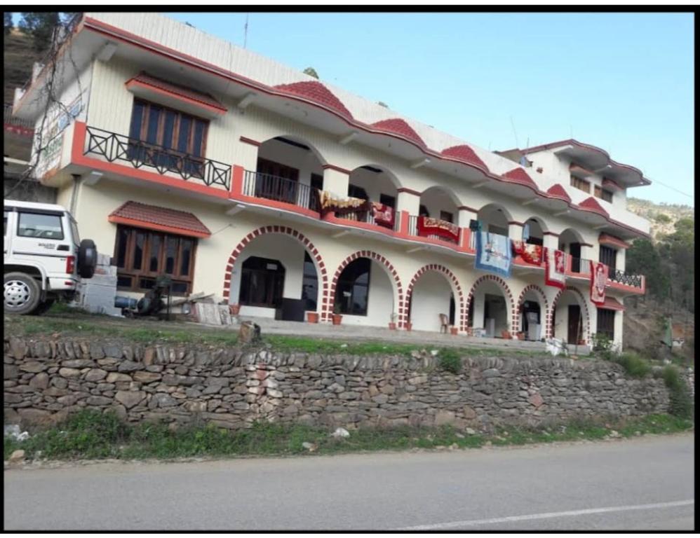a large building with a stone wall in front of it at Hotel Krish Motel and Restaurant, Uttarkashi in Uttarkāshi