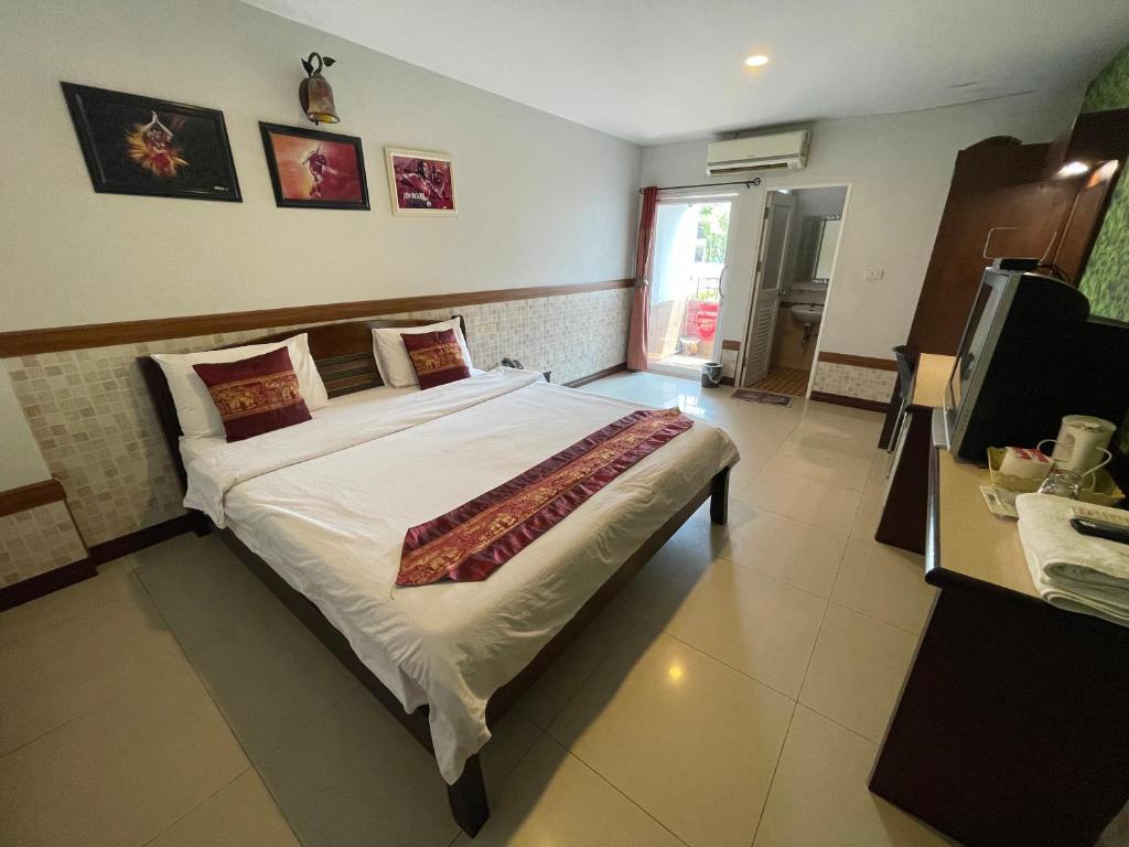 a bedroom with a large bed and a television at Man u Apartment in Chaiyaphum