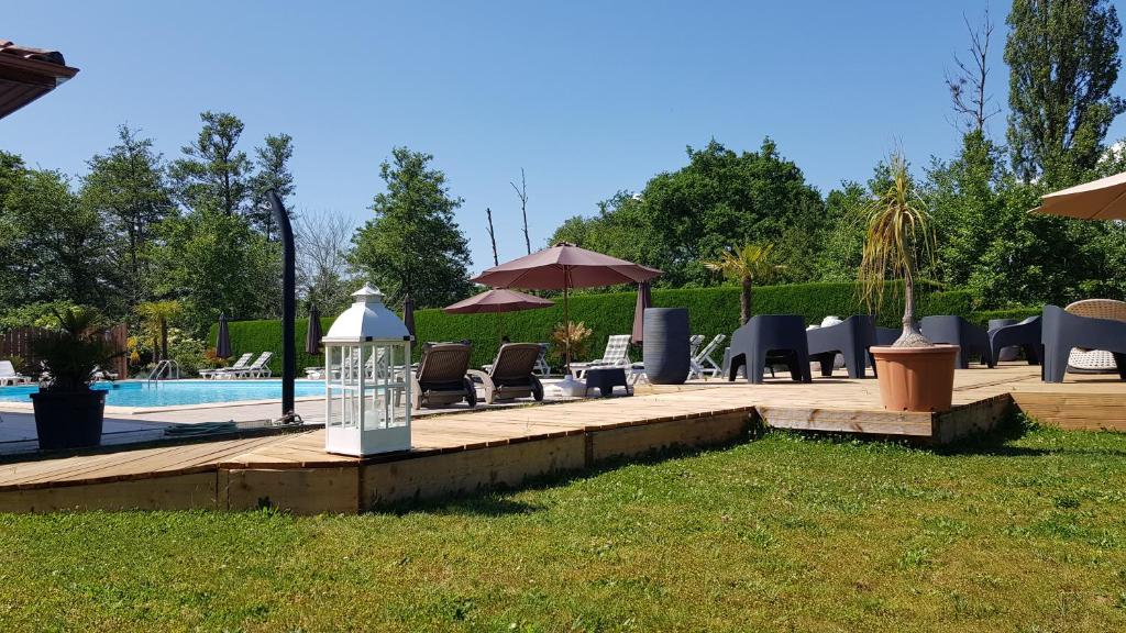 a backyard with a pool and chairs and a table at Hôtel LES LODGES D'EAUZE in Eauze