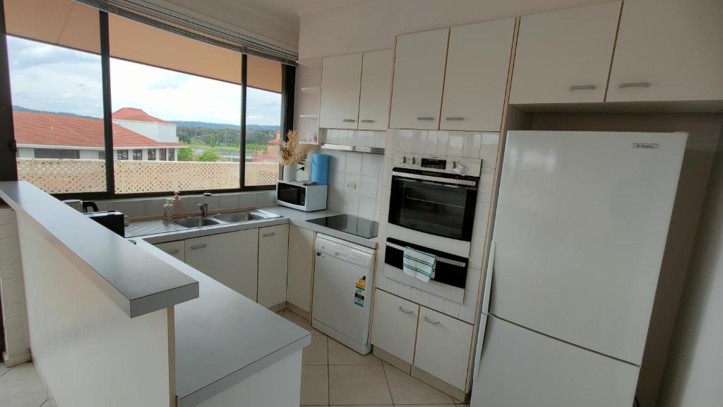 Il comprend une cuisine équipée d'appareils électroménagers blancs et une grande fenêtre. dans l'établissement Tuggeranong Short Stay #07 - Sleeps 6, à Tuggeranong