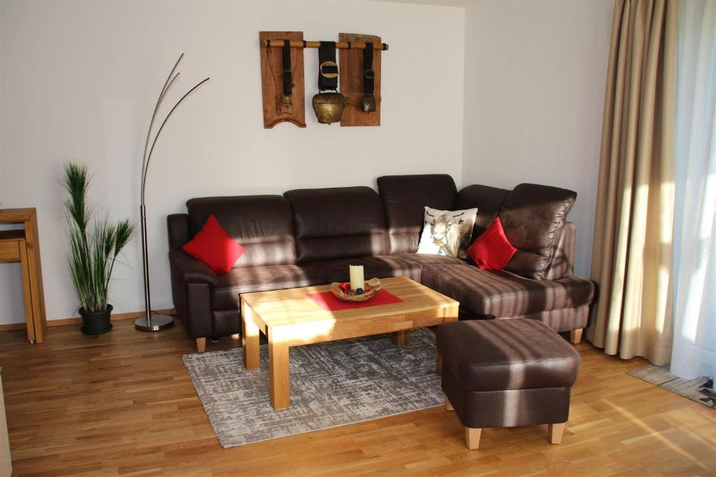 a living room with a leather couch and a coffee table at FeWo Glockenstüble mit Schwimmbad und Sauna in Oberstaufen