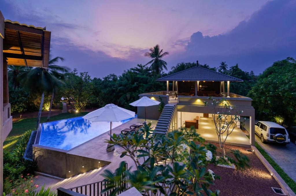 a villa with a swimming pool at night at Kiss Blossom in Mirissa