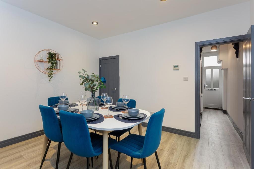a dining room with a table and blue chairs at Methuen Mews - 2 double bedroom townhouse within walking distance to beach, on-street parking in Portsmouth in Portsmouth