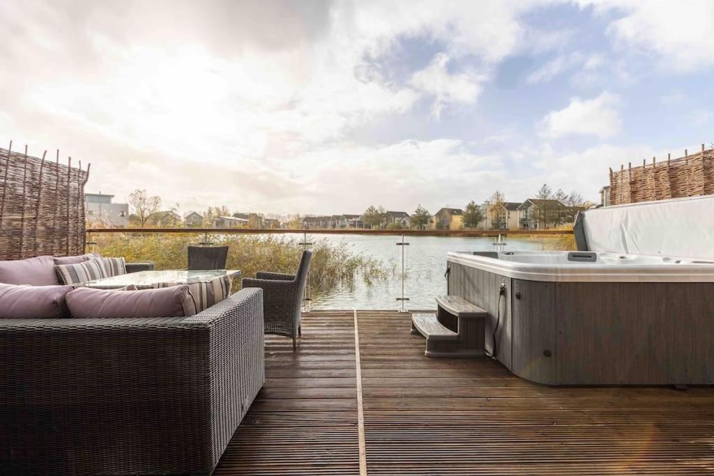 a bath tub sitting on a deck next to a body of water at Otters Holt in Somerford Keynes