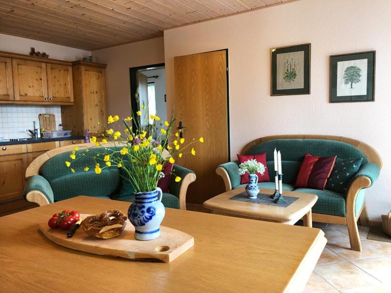 een woonkamer met een tafel met een vaas met bloemen bij Ferienwohnung Jessen in Oberstaufen