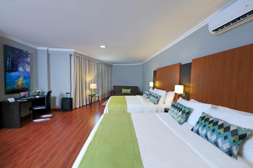 a large hotel room with two beds and a desk at Aranjuez Hotel & Suites in David