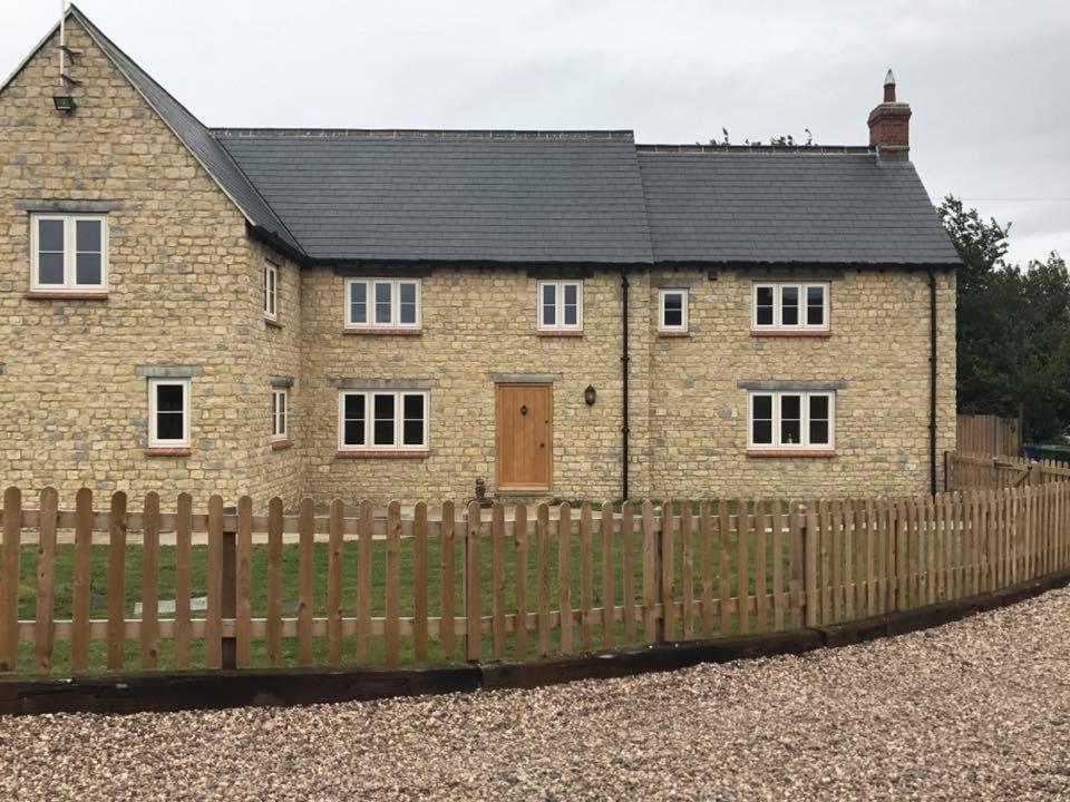 a brick house with a wooden fence in front of it at Denbrae in Brackley