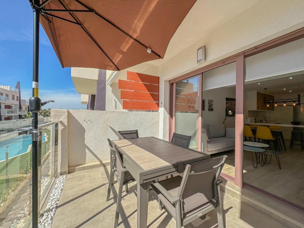 a wooden table and chairs on a balcony with an umbrella at Bianca Beach 222 - Mil Palmeras, vista piscina y mar in La Horadada