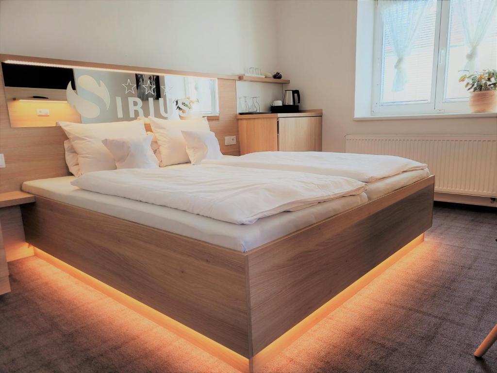 a large bed with a wooden frame in a bedroom at Penzion Sirius in Vyškov