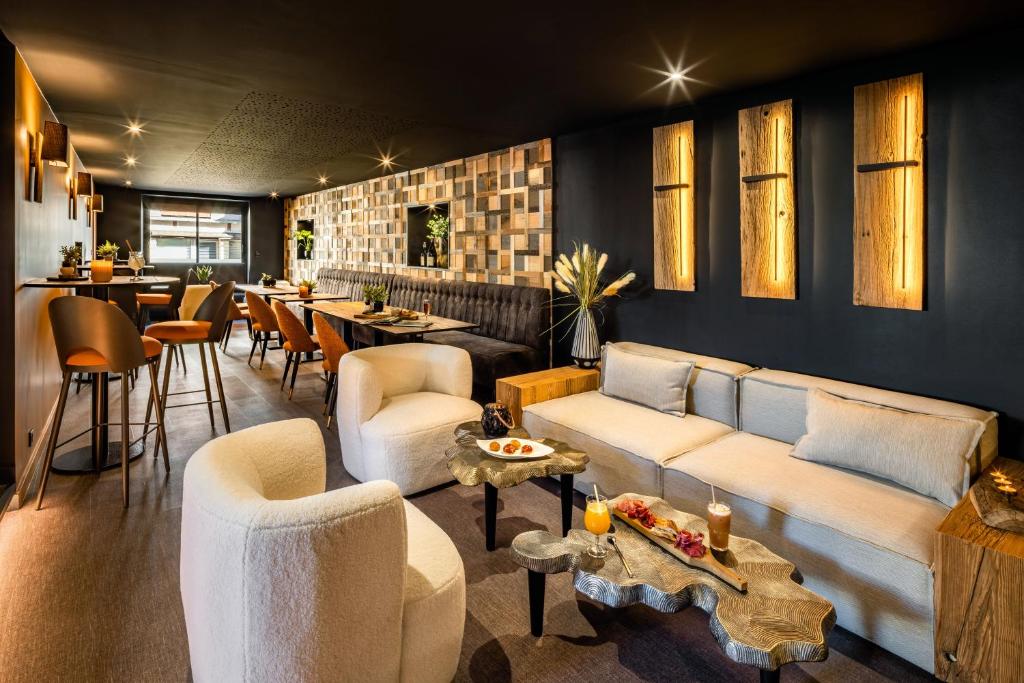 ein Wohnzimmer mit Sofas, Tischen und einer Bar in der Unterkunft Logis Hôtel LBB - les 2 lacs in Clairvaux-les-Lacs