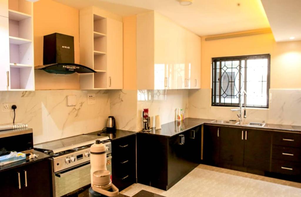 une grande cuisine avec des armoires noires et une fenêtre dans l'établissement SHOAL Apartments, Mawanda Road, à Kampala