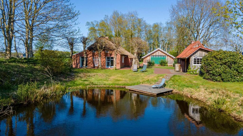 een huis aan de oever van een rivier naast een gebouw bij Reetdach Ostfriesenhaus in Südbrookmerland