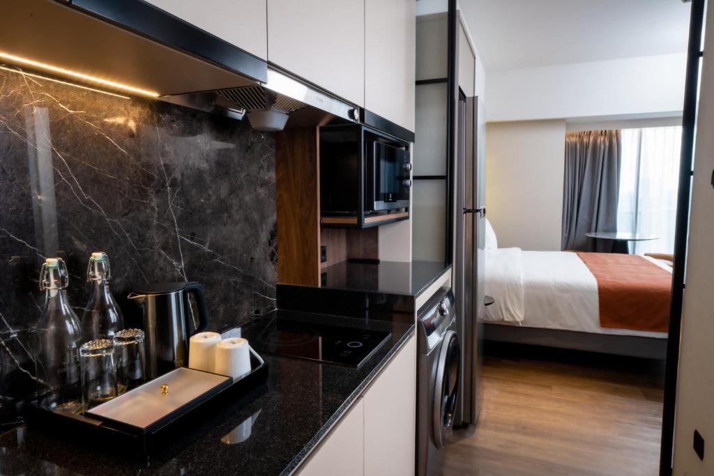 Herloom Hotel & Residence BSD Tangerang في تانغيرانغ: مطبخ مع حوض وغرفة مع سرير