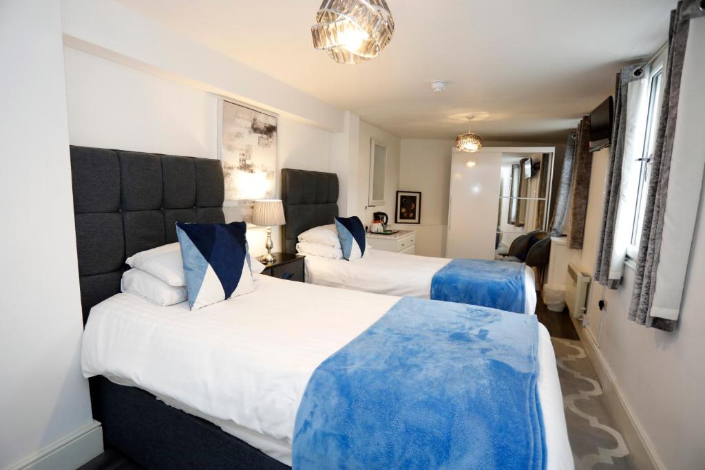two beds in a hotel room with blue and white at Bexley Village Hotel in Bexley
