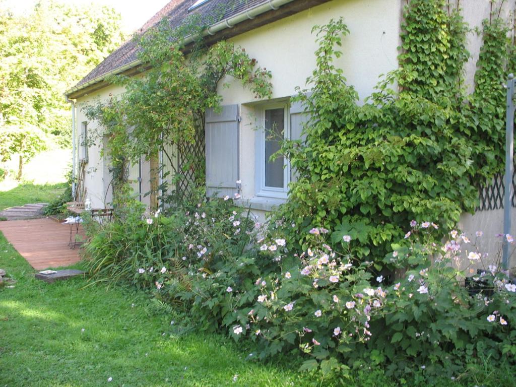 ein weißes Haus mit einem Fenster und ein paar Blumen in der Unterkunft Le Brame - Chambres d'Hôtes in Avilly-Saint-Léonard