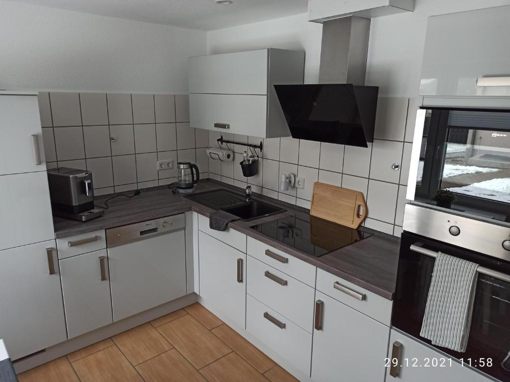a kitchen with white cabinets and a sink and a tv at NEU! Ferienhaus Römer in Bad Sülze