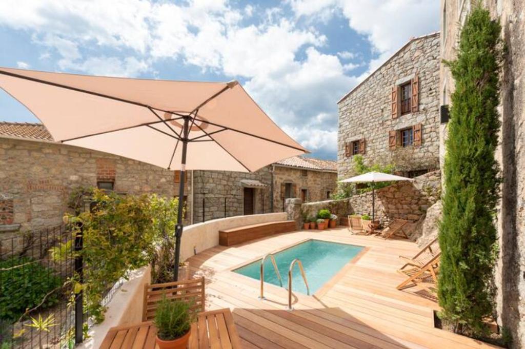 een patio met een parasol en een zwembad bij Maison Madamicella in Fozzano