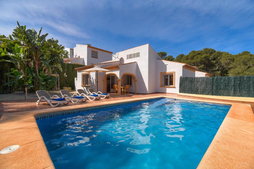 a villa with a swimming pool in front of a house at Monte Rojo in Jávea