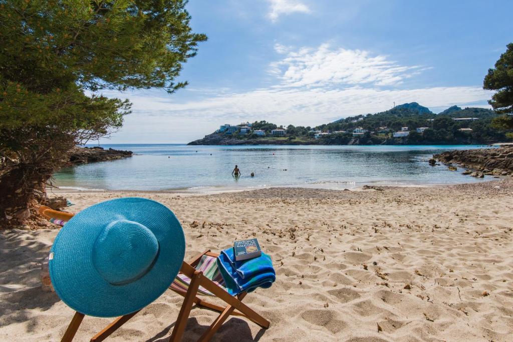 a blue hat and a chair on a beach at Casa Aladern on the beach MHM in Font de Sa Cala