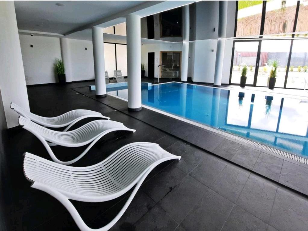 - deux chaises blanches dans un bâtiment avec piscine dans l'établissement Westin House-Resort, à Kołobrzeg
