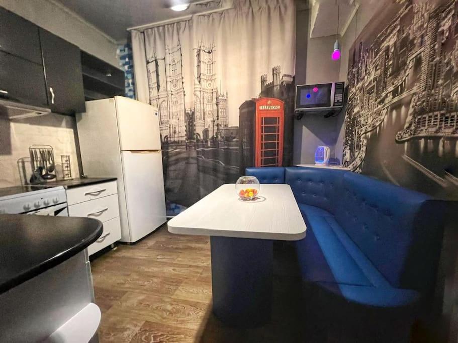 a kitchen with a blue couch and a red phone booth at Квартира in Ustʼ-Kamenogorsk